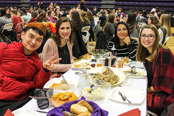Photo of international students at a 冰球突破app harvest dinner, 吃饭时对着镜头微笑