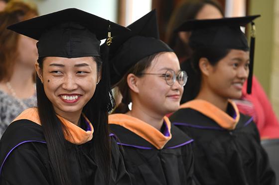 Photo of three 冰球突破app international students at graduation in caps and gowns
