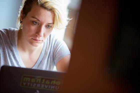 图为一位冰球突破app的学生在咖啡厅里看着她的笔记本电脑.
