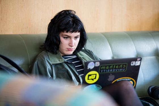 图为一位冰球突破app的女学生坐在图书馆的沙发上, 在笔记本电脑上工作